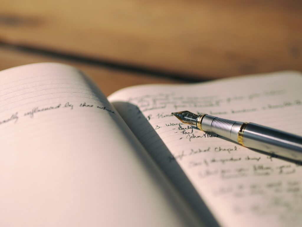 A journal with a pen resting on top, showing written text on the page
